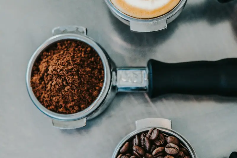 Flat lay of a latte, ground coffee and whole beans in portafilters