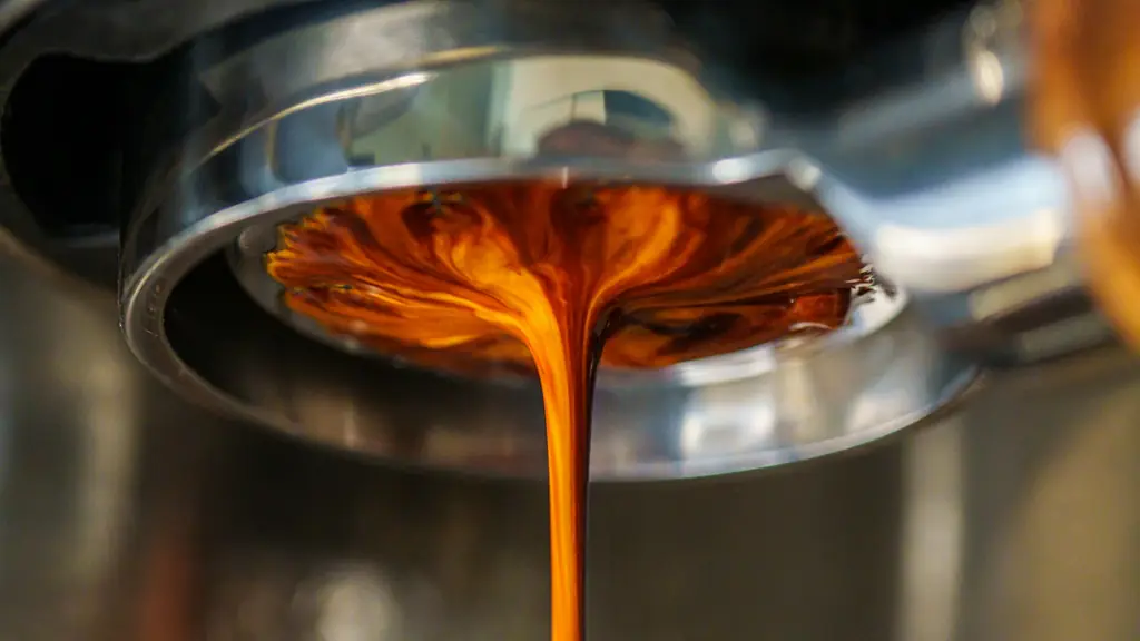 Fresh espresso pouring from a portafilter into a cup, with golden crema