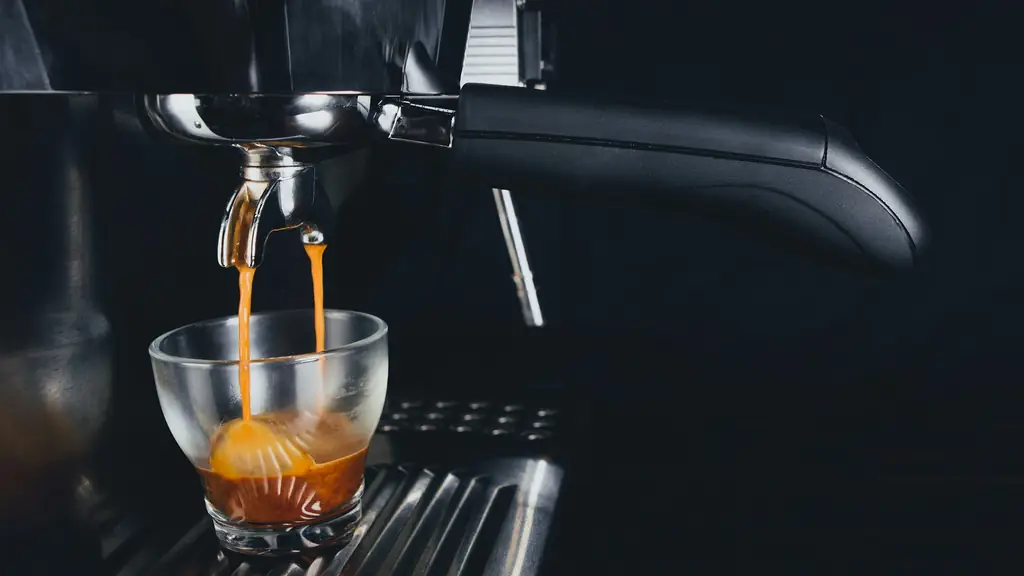 Two streams of espresso pouring into a glass under a portafilter, dark background