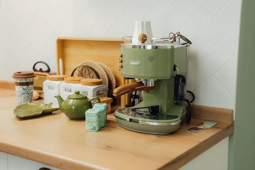 Green retro espresso machine on a wooden kitchen counter beside a teapot and tea tins (illustrative)