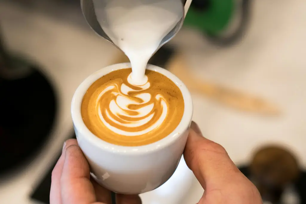 Steamed milk being poured into a cappuccino, forming latte art