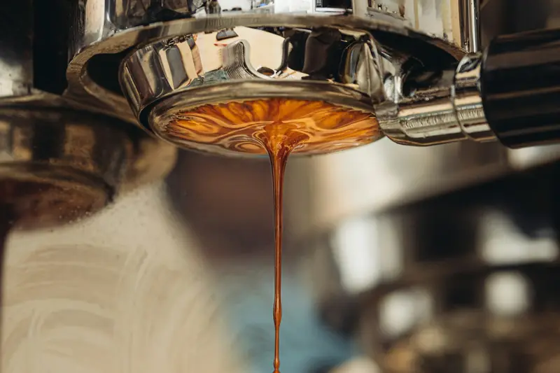 Espresso dripping from a metal portafilter on a home espresso machine