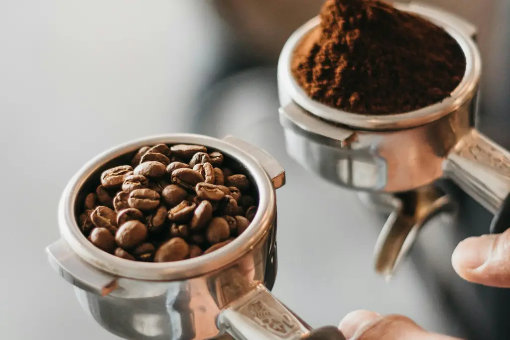 Two portafilters, one holding whole coffee beans and one holding ground coffee