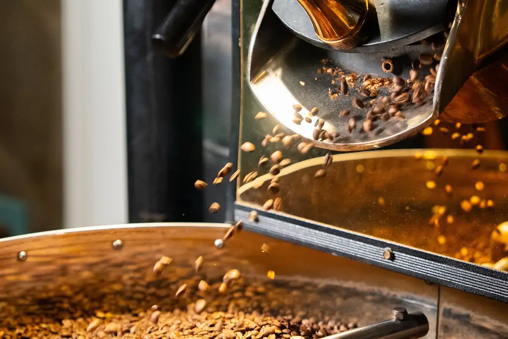 Freshly roasted beans tumbling from a drum roaster's door into the cooling tray